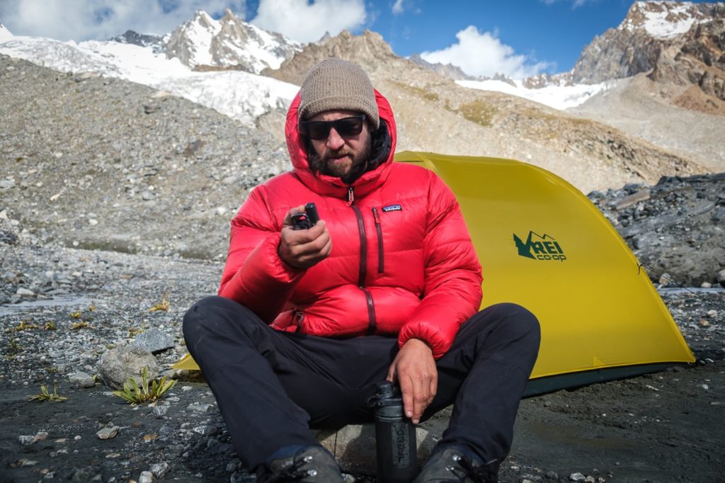 man on glacier with tent and satellite phone